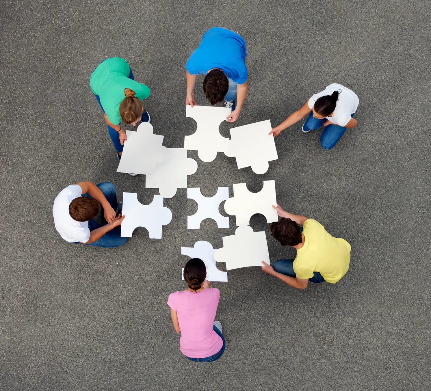 People assembling large puzzle pieces together