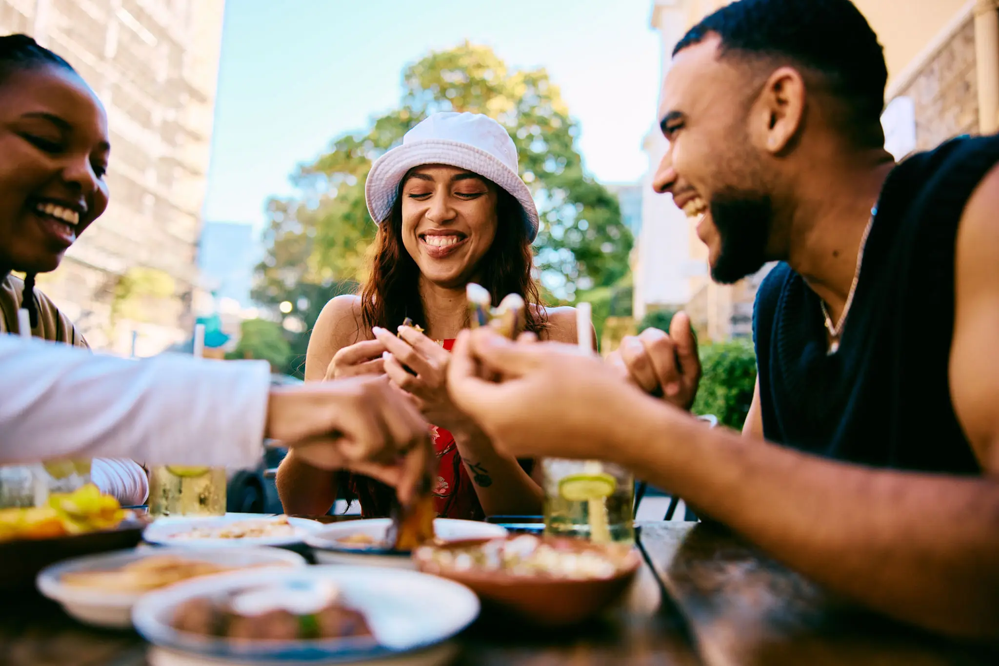 Friends laughing and sharing food at outdoor table